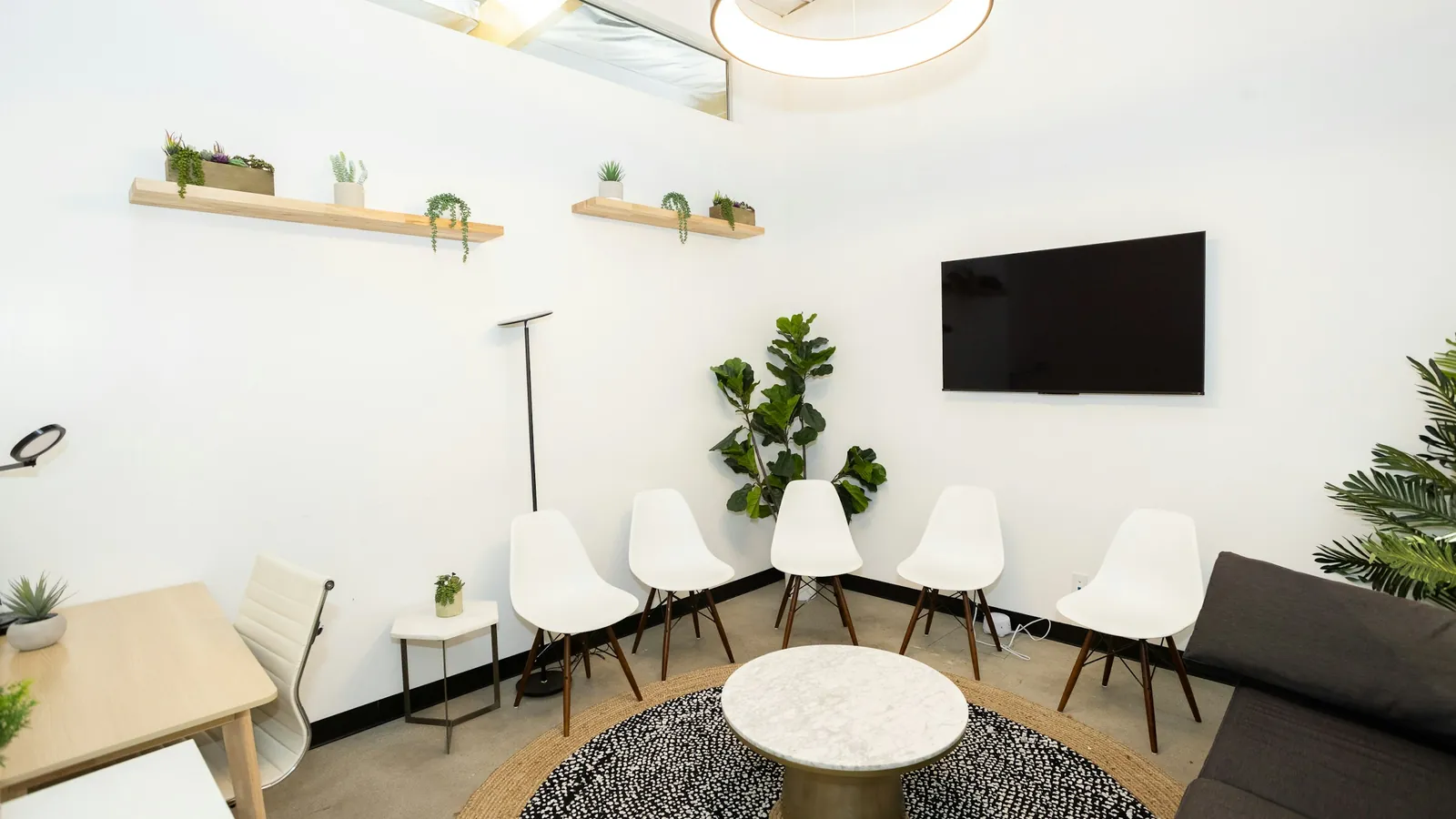 Salle d'attente claire avec chaises blanches et plantes vertes